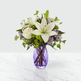 White lily bouquet in a purple glass vase
