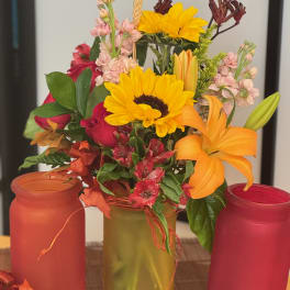Mixed bouquet with sunflowers, lilies, roses, and pink filler flowers in a vase