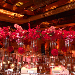 Tall pink floral centerpieces in clear glass vases at a banquet table