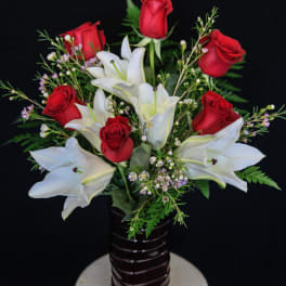 Red roses and white lilies arranged in a dark vase