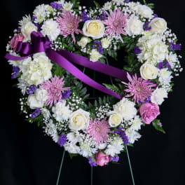 Heart-shaped floral wreath with pink and white flowers and a purple ribbon