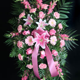 Pink floral standing spray with lilies, roses, and carnations on a ribboned easel