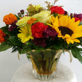 Mixed bouquet with sunflowers, roses, and carnations in a gold vase