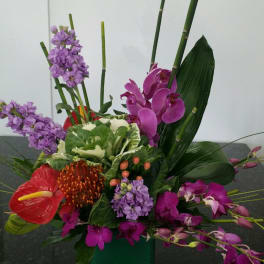 Tropical floral arrangement with orchids and anthurium in a green vase