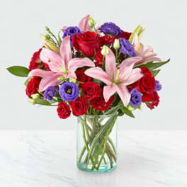 Bouquet of red roses and pink lilies in a clear glass vase