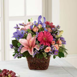 Mixed bouquet in a woven basket with pink lilies and purple flowers
