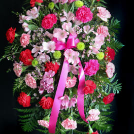 Standing floral wreath with pink and red carnations and a pink ribbon