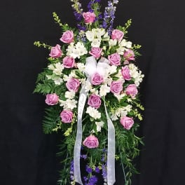Standing floral spray with pink roses, white blooms, and purple accents on a black background