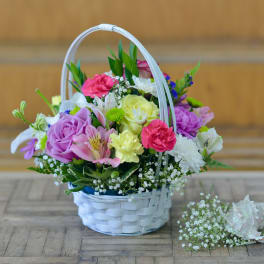 Mixed flower basket with roses, carnations, and daisies in a white wicker basket