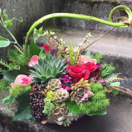 Mixed floral arrangement with red roses, succulents, and berries in a low container