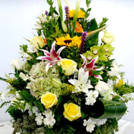 Large mixed floral arrangement with yellow roses and white lilies in a vase
