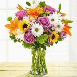 Mixed bouquet of orange lilies, purple roses, and white daisies in a glass vase