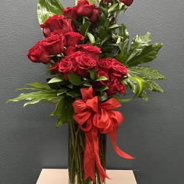 Red roses in a clear glass vase with a red ribbon