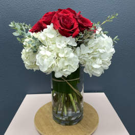 Red roses and white hydrangeas in a clear glass vase