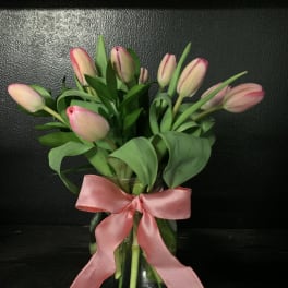 Pink tulips in a glass vase with a pink ribbon bow