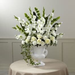 White floral arrangement in a white urn vase with trailing greenery