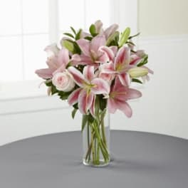 Pink lilies and a rose in a clear glass vase