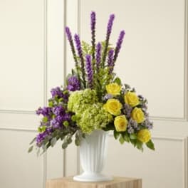 Purple and yellow floral arrangement in a white vase