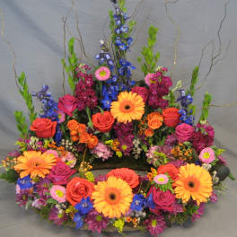 Colorful floral wreath with roses, gerbera daisies, and blue flowers