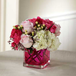 Pink and white rose bouquet in a square glass vase