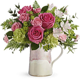 Pink roses and white lilies arranged in a ceramic pitcher vase