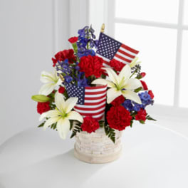 Red, white, and blue floral arrangement with small American flags in a basket