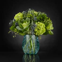 Green floral arrangement in a blue glass vase