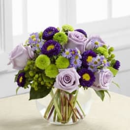Lavender roses and purple flowers in a clear glass vase