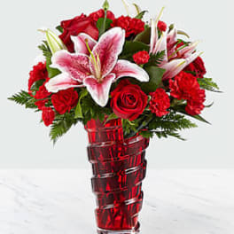Red roses and pink lilies in a red glass vase