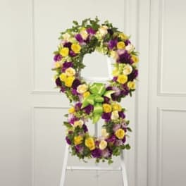 Floral wreath on a white easel with yellow, purple, and white blooms