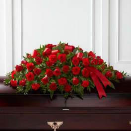 Red rose casket spray with a red ribbon on a dark casket