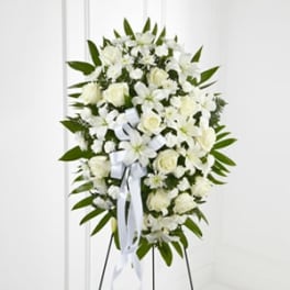 White floral standing spray with a ribbon on a metal easel