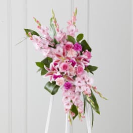 Pink floral spray with lilies and roses on a white stand