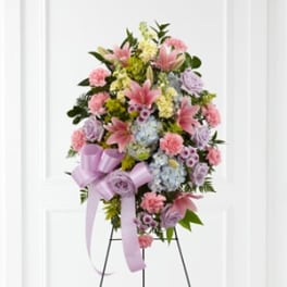 Standing floral spray with pink lilies, carnations, and pastel blooms on an easel