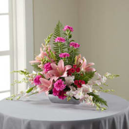 Pink lilies and carnations arranged in a low white vase