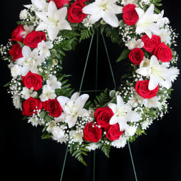 Red roses and white lilies arranged in a circular funeral wreath