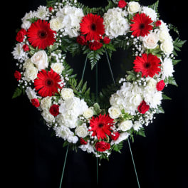 Heart-shaped floral wreath with red and white flowers on a stand