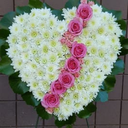 Heart-shaped floral spray of white chrysanthemums and pink roses on a stand