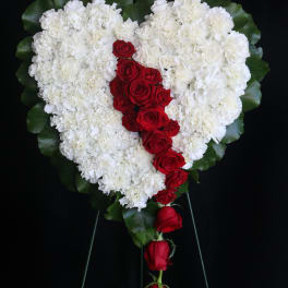 Heart-shaped white floral spray with red roses down the center