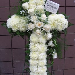 White floral cross on a stand with roses and chrysanthemums