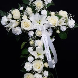White floral standing spray with roses, lilies, and carnations on a black background