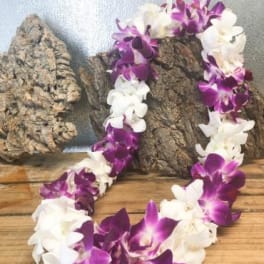 Purple and white orchid lei draped over wood