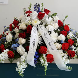 Large red, white, and blue funeral spray with ribbon streamers