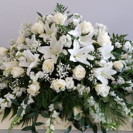 Large white floral spray with lilies and roses on a table