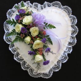 Heart-shaped lace pillow with a floral spray of white roses and purple flowers