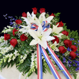 Large funeral spray of red roses and white lilies with a tricolor ribbon