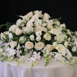 Large white floral casket spray with roses and calla lilies