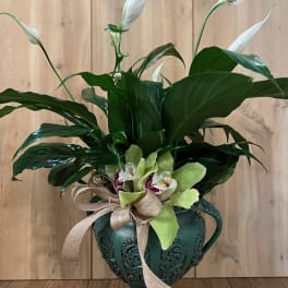 White peace lilies and orchids in a decorative green urn