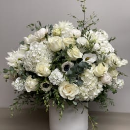 Large white and cream flower arrangement in a white cylinder vase