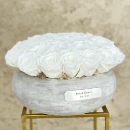 White roses arranged in a round gray box on a gold stand